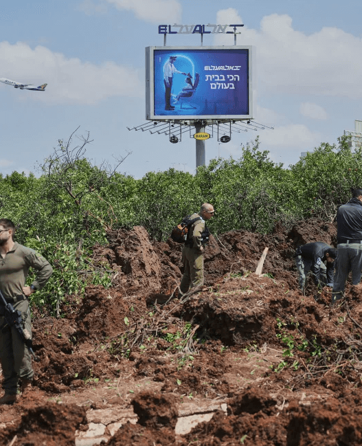 Debris from missile strike near Ben Gurion Airport with smoke rising.