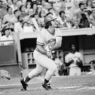 Pete Rose in a Cincinnati Reds uniform swinging at a pitch during a 1970s MLB game.