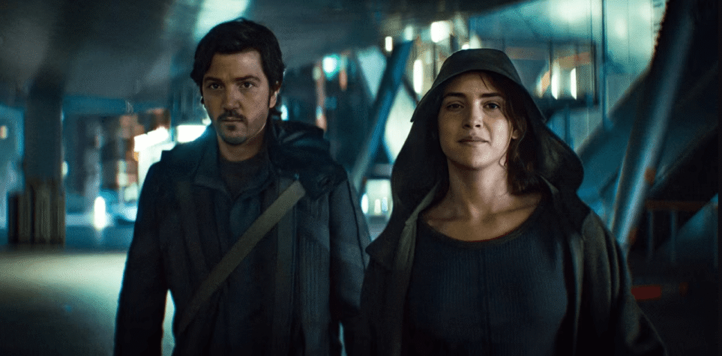 Cassian Andor stands amid a chaotic street scene during the Ghorman uprising in Andor Season 2, Episode