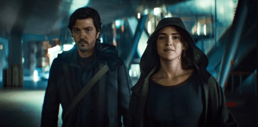 Cassian Andor stands amid a chaotic street scene during the Ghorman uprising in Andor Season 2, Episode