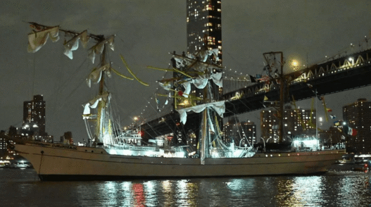 Mexican Navy tall ship Cuauhtémoc with broken masts after striking the Brooklyn Bridge, with crew members visible in the rigging and emergency response underway.